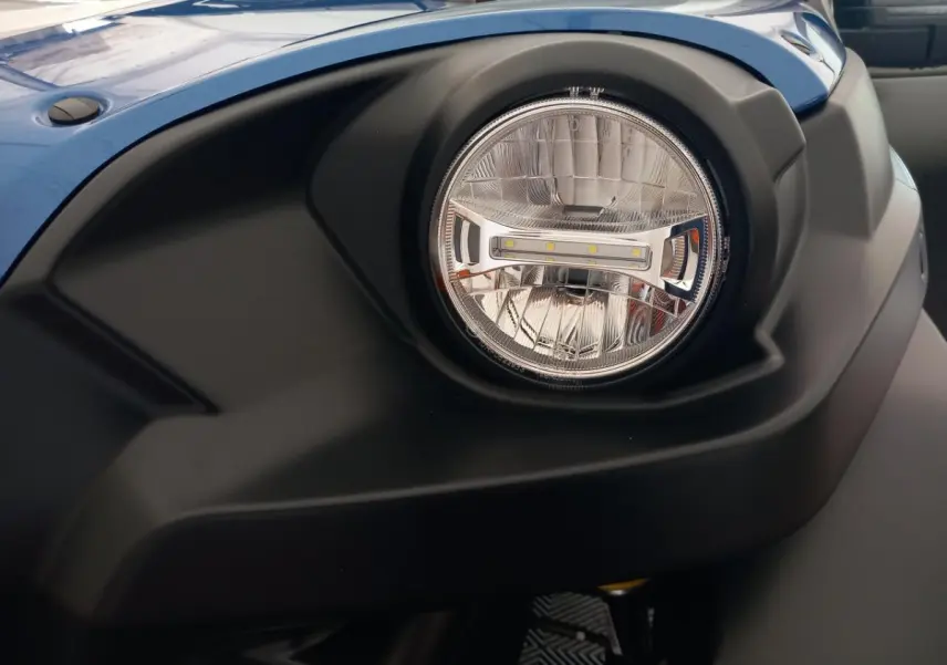 Gros plan sur le phare avant droit de l'AIXAM MEGA bleu électrique, soulignant son design moderne et robuste.