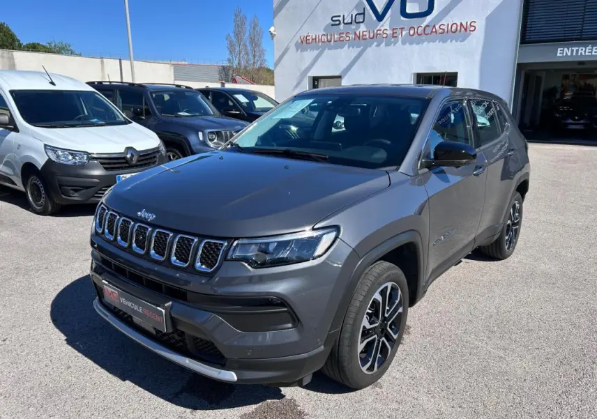 Jeep Compass gris 3/4 avant droit, jantes alliage 18 pouces, calandre distinctive et phares LED visibles.