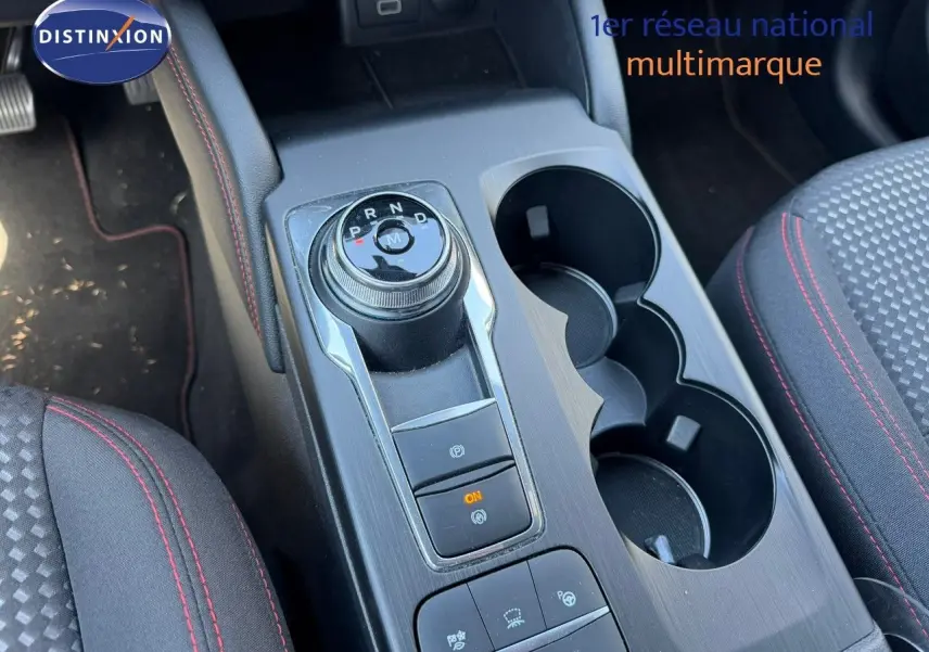Vue rapprochée de la console centrale du Ford Kuga gris magnétique, avec sélecteur rotatif de boîte auto et porte-gobelets.