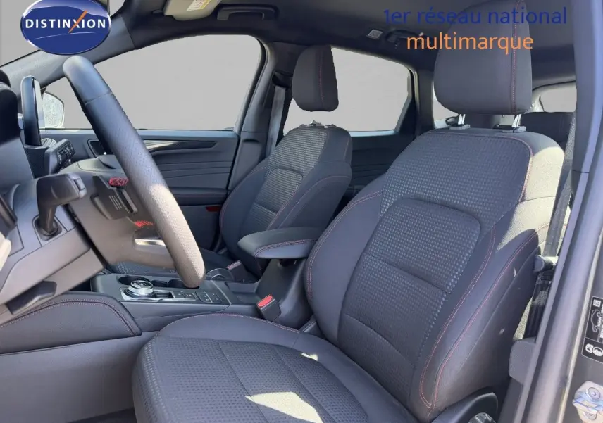 Vue intérieure côté conducteur du Ford Kuga 2024, sièges tissu noir avec surpiqûres rouges et console centrale moderne.