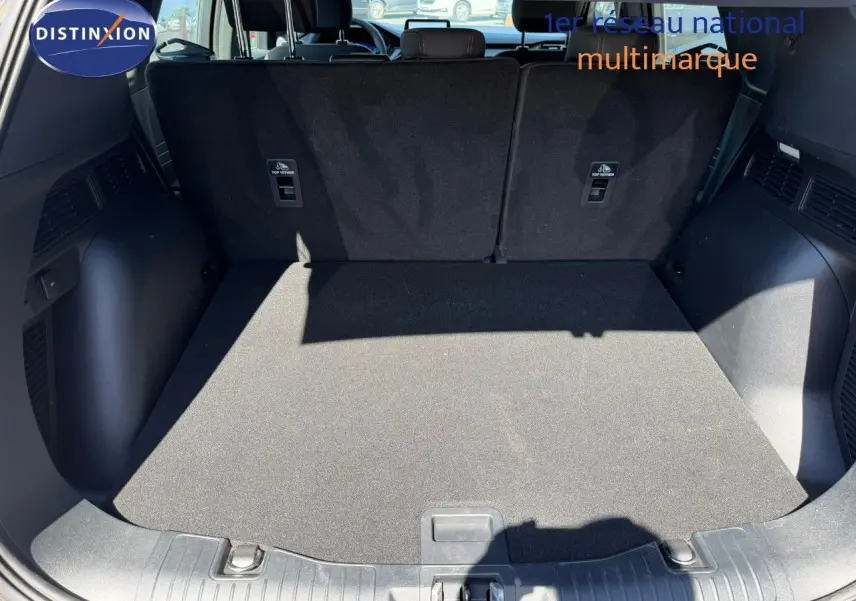 Coffre ouvert du Ford Kuga 2024 gris magnétique, vue arrière montrant l’espace de chargement et les dossiers de sièges noirs.