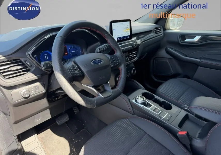 Intérieur Ford Kuga 2024 vue côté conducteur, volant cuir noir avec surpiqûres rouges et écran tactile central.