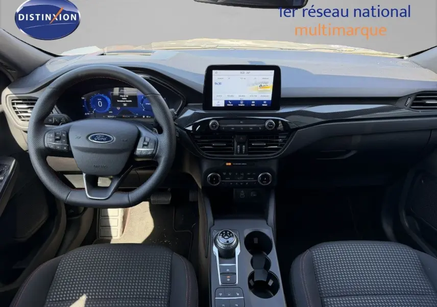 Vue intérieure du tableau de bord et volant du Ford Kuga 2024, avec écran tactile et sellerie tissu gris.