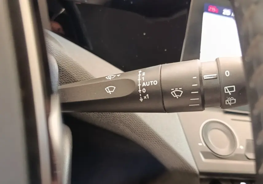 Gros plan sur la commande des essuie-glaces à gauche du volant dans l’habitacle d’une Peugeot 308 blanche.
