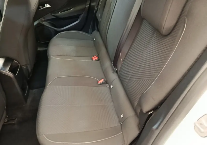 Vue intérieure côté arrière droit montrant la banquette noire avec coutures contrastantes de la Peugeot 308 blanche 2023.