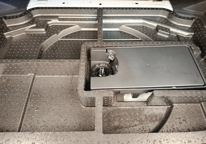 Vue rapprochée du compartiment de rangement sous le plancher de coffre de la Peugeot 308 blanche 2023.