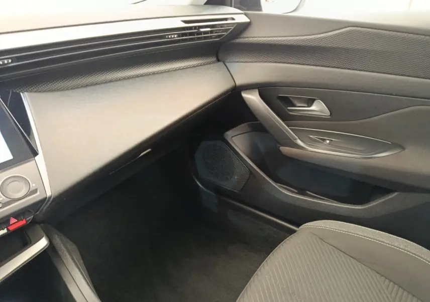 Intérieur côté passager de la Peugeot 308 blanche 2023, montrant la planche de bord et la porte en tissu noir.