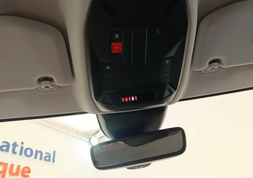 Vue intérieure du plafonnier et rétroviseur intérieur d'une Peugeot 308 blanche de 2023 avec boutons SOS et éclairage intégré.