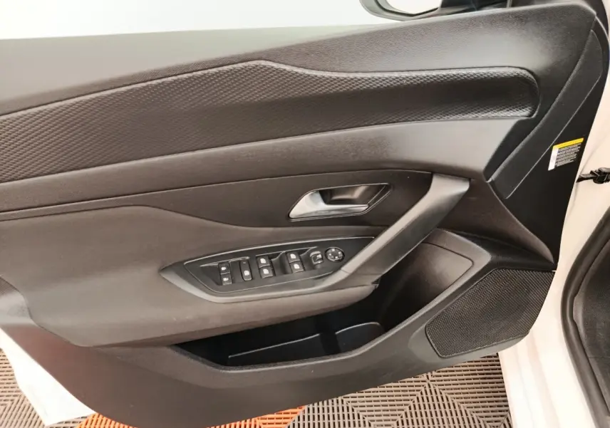 Vue intérieure côté gauche de la porte avant blanche d'une Peugeot 308 2023 avec commandes électriques et poignée argentée.