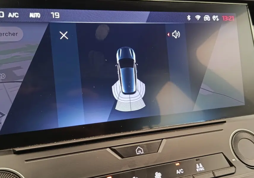 Écran tactile intérieur montrant la vue aérienne du véhicule Peugeot 308 blanc avec capteurs de stationnement arrière actifs.