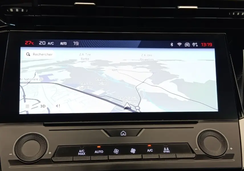 Affichage tactile central de la Peugeot 308 blanche, vue rapprochée du système de navigation et climatisation digitale.
