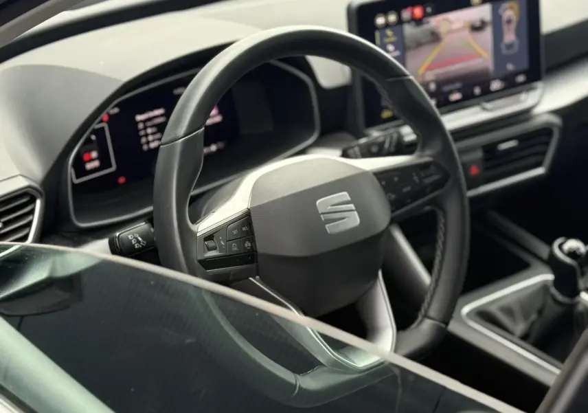 Vue intérieure rapprochée du volant en cuir et du tableau de bord numérique d'une SEAT LEON 1.5 TSI 115 Style 2025.