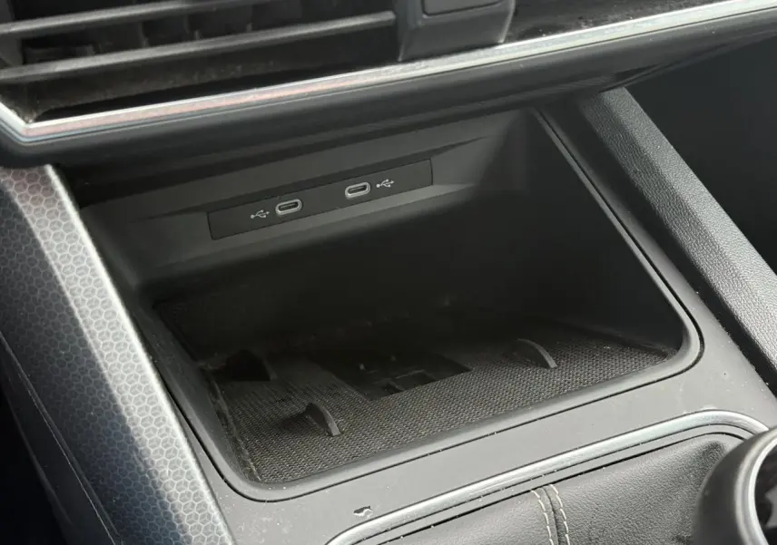 Gros plan sur la console centrale noire du SEAT LEON 1.5 TSI 115 Style, montrant les ports USB-C et le chargeur à induction.