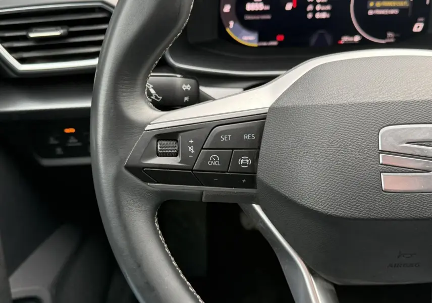 Gros plan sur le volant cuir multifonction de la SEAT Leon 1.5 TSI 115 Style, avec commandes de régulateur de vitesse.