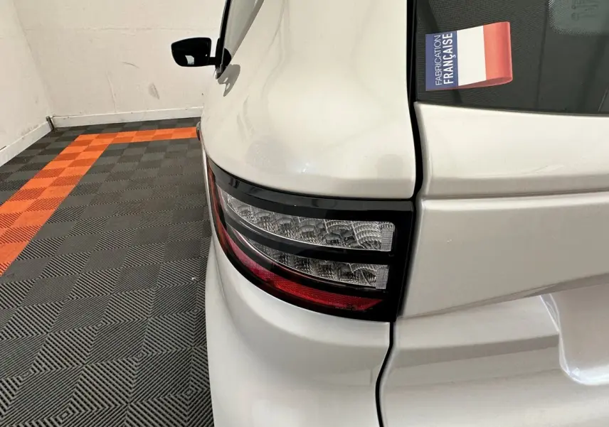 Gros plan sur le feu arrière droit blanc de l'AIXAM AMBITION 0.5 CITY PACK 2026 avec rétroviseur caméra côté conducteur.