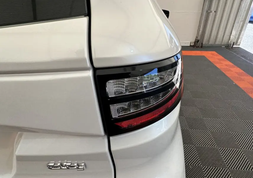 Gros plan sur le feu arrière droit d’une Aixam Ambition blanc 2026 avec détails du hayon et éclairage bicolore.