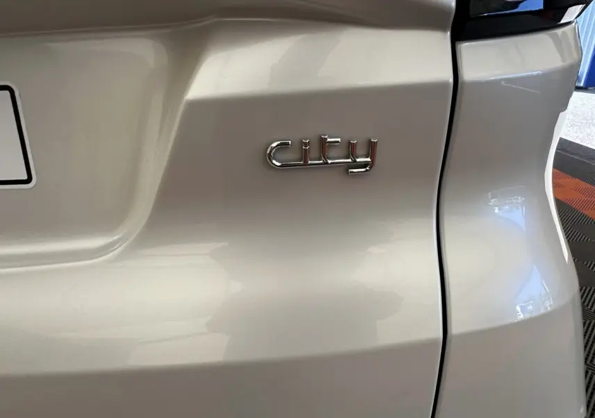 Gros plan sur l'arrière blanc de l'AIXAM AMBITION 0.5 CITY PACK avec l’inscription chrome "city".