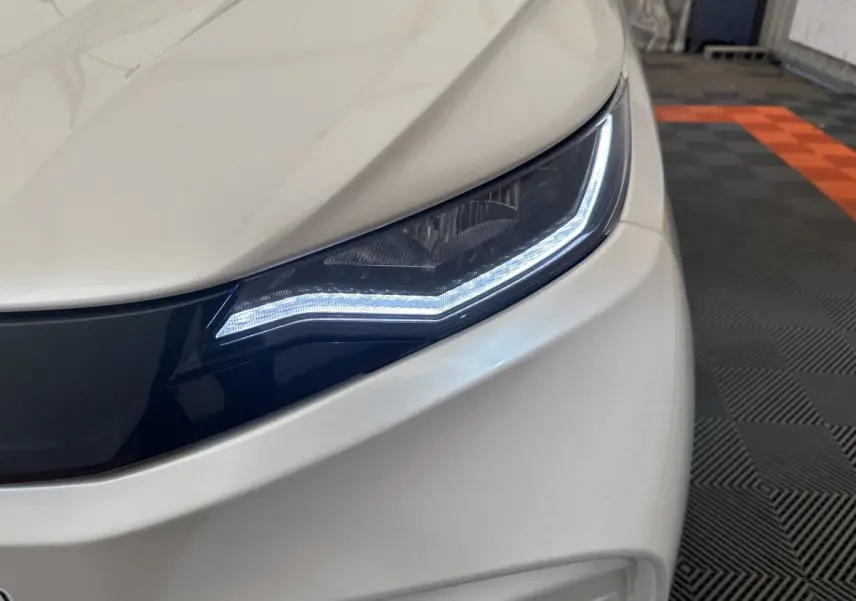 Gros plan sur le phare avant droit blanc de l'AIXAM AMBITION 0.5 CITY PACK 2026 avec éclairage LED distinctif.