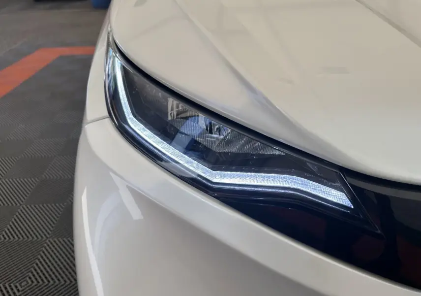 Gros plan sur le phare avant droit blanc de l'AIXAM AMBITION 0.5 CITY PACK 2026 avec éclairage LED distinctif.