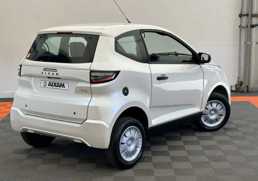 Vue 3/4 arrière droite d'une Aixam Ambition 0.5 City Pack blanche avec rétroviseur caméra côté gauche.