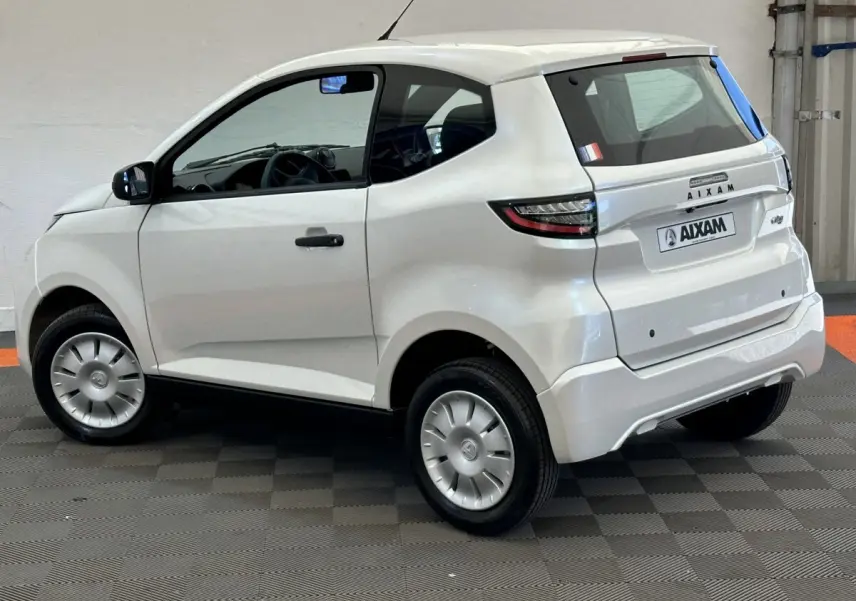 Vue 3/4 arrière droite de l'Aixam Ambition 0.5 City Pack blanche avec rétroviseur caméra côté gauche visible.