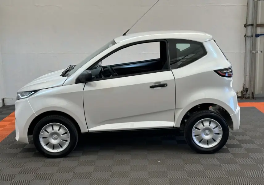Vue de profil côté gauche de l'AIXAM AMBITION 0.5 CITY PACK blanche avec rétroviseur caméra côté conducteur.