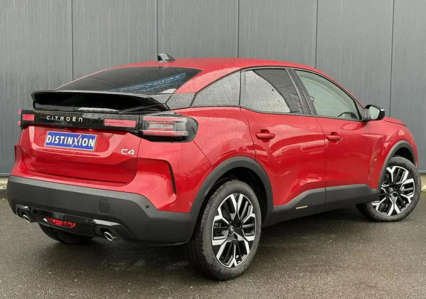 Vue 3/4 arrière droite d'une Citroën C4 Hybrid 145 rouge Elixir avec jantes alliage 18'' et toit noir contrasté.