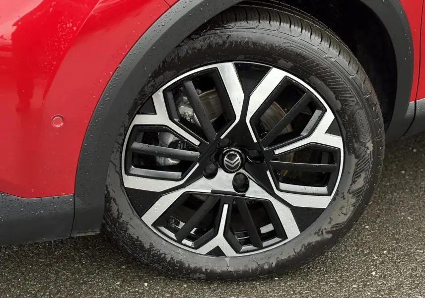 Gros plan sur la roue avant droite d'une Citroën C4 rouge Elixir avec jante alliage 18 pouces diamantée.