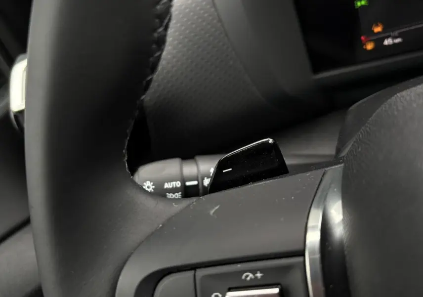 Gros plan sur le volant noir de la Citroën C4 Hybrid 2025, avec palettes de changement de rapports visibles.