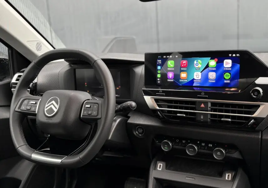 Vue intérieure centrée sur le volant Citroën et l’écran tactile 10" du tableau de bord du C4 Hybrid rouge Elixir.