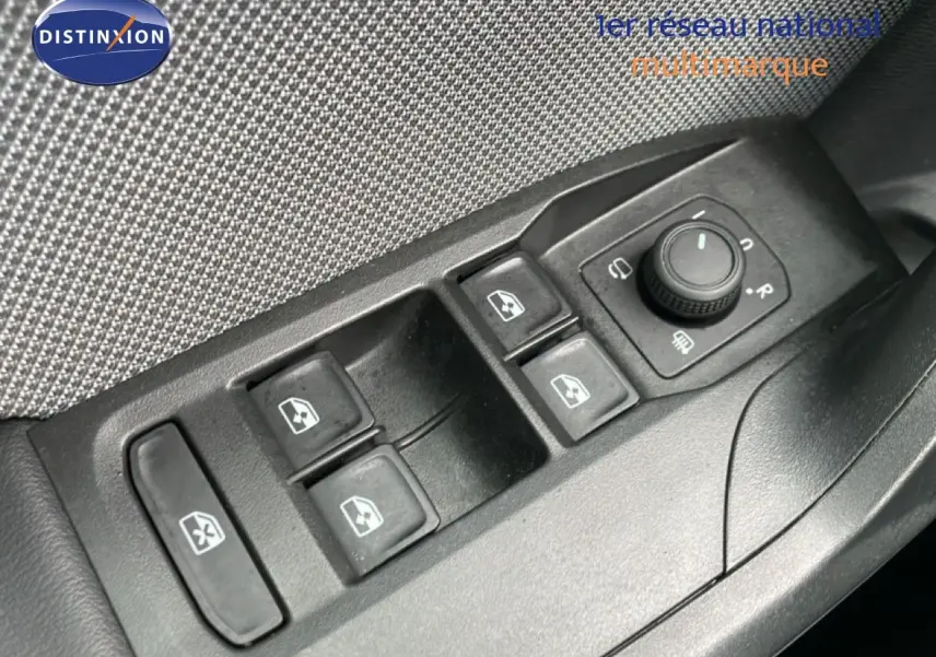 Gros plan sur les commandes de lève-vitres et réglage des rétroviseurs côté conducteur d'une SEAT Leon gris métallique.