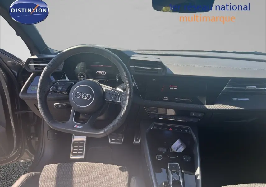 Vue intérieure du poste de conduite de l'Audi A3 Sportback gris Daytona, avec volant multifonction et tableau de bord digital.