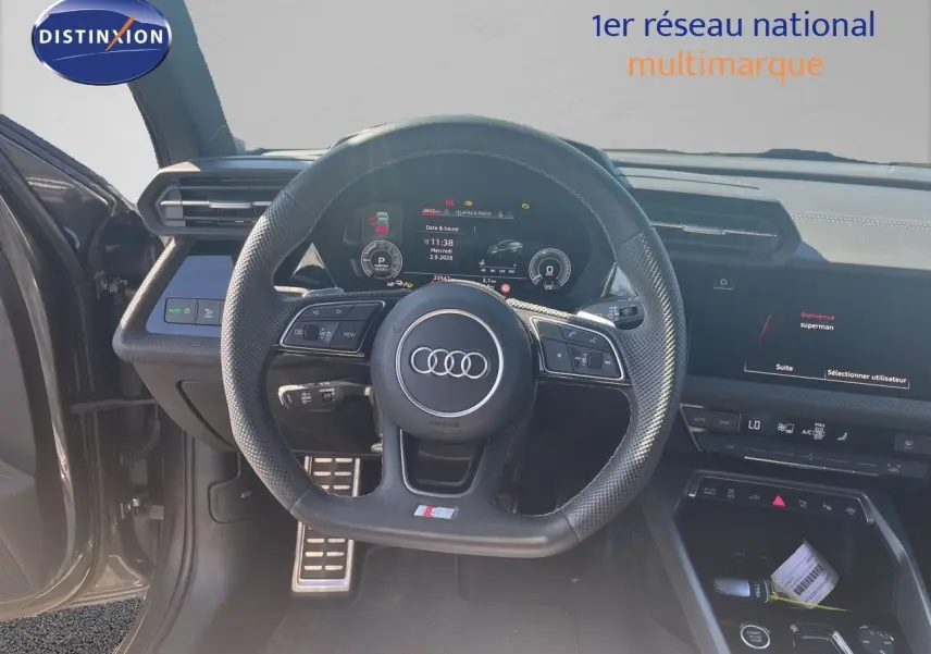 Vue intérieure centrée sur le volant cuir noir perforé et le tableau de bord numérique de l'Audi A3 Sportback 2025.