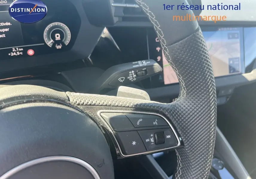Gros plan sur le volant en cuir perforé avec commandes intégrées et tableau de bord numérique d'une Audi A3 Sportback 2025.