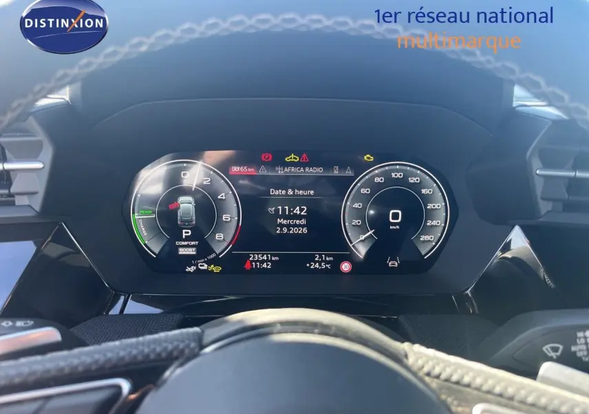 Vue rapprochée du tableau de bord numérique d'une Audi A3 Sportback 40 TFSIe gris Daytona, affichant la vitesse et l'heure.