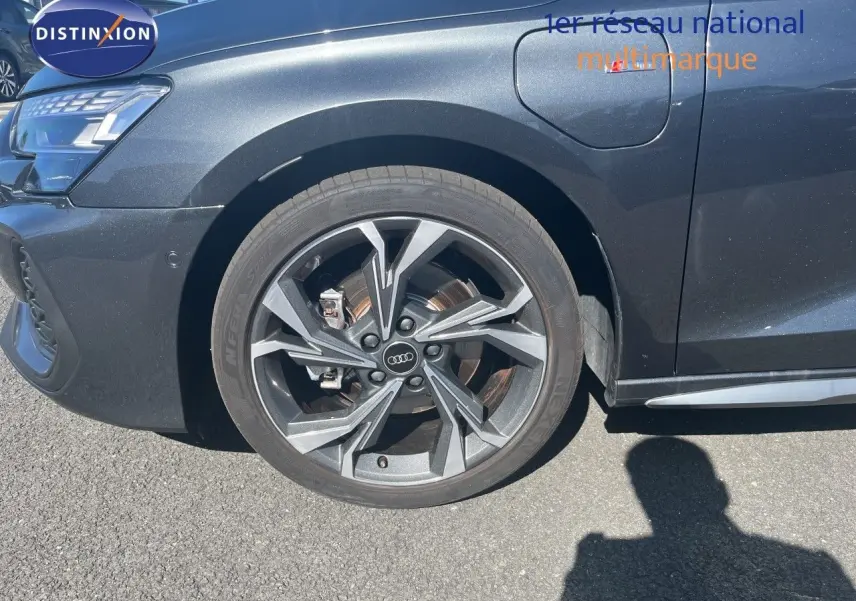 Gros plan sur la roue avant gauche et la partie avant gris Daytona métallisé de l'Audi A3 Sportback 40 TFSIe S-Line 2025.