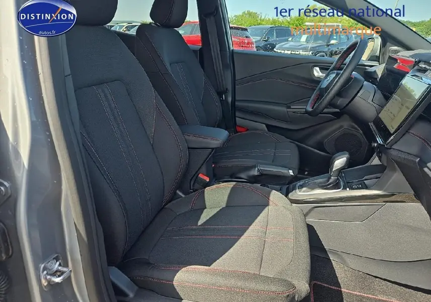 Intérieur avant droit du Ford Puma gris cactus 2025 avec sièges tissu noirs et surpiqûres rouges visibles.