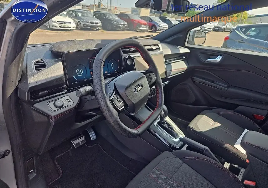 Intérieur côté conducteur du Ford Puma gris cactus 2025, volant cuir avec surpiqûres rouges et écran tactile central.