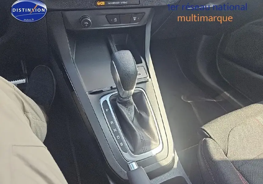 Le levier de boîte automatique au centre de la console d'une Ford Puma 2025, tissu noir avec surpiqûres rouges visible.