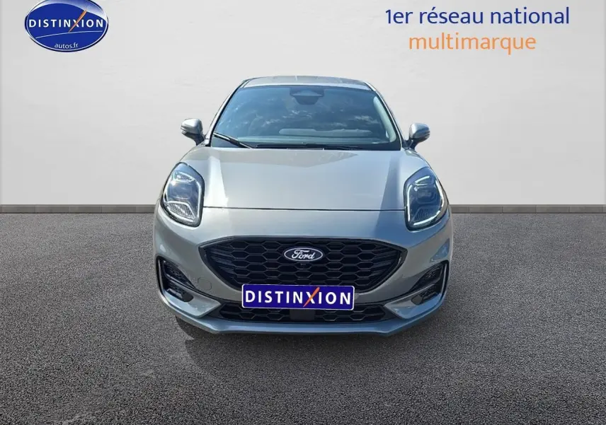 Vue frontale du Ford Puma 2025 gris cactus avec calandre noire et phares LED allumés sur fond neutre.