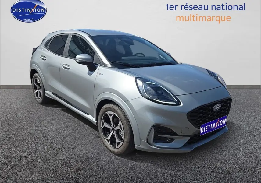 Ford Puma gris cactus en 3/4 avant droit avec jantes 17 pouces et phares LED allumés sur fond neutre.