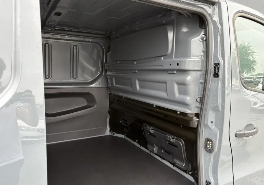 Intérieur du fourgon Renault Trafic L2H1 2025 en Gris Urbain, vue côté droit avec plancher antidérapant et cloison tôlée.