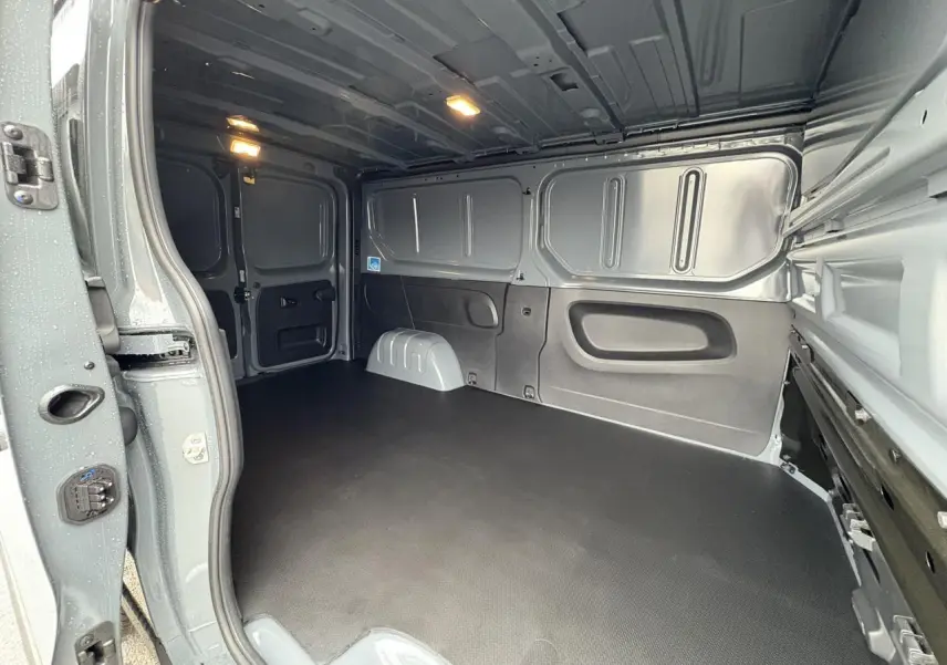 Intérieur du fourgon Renault Trafic L2H1 2025 gris urbain, vue de la zone de chargement avec plancher antidérapant noir.
