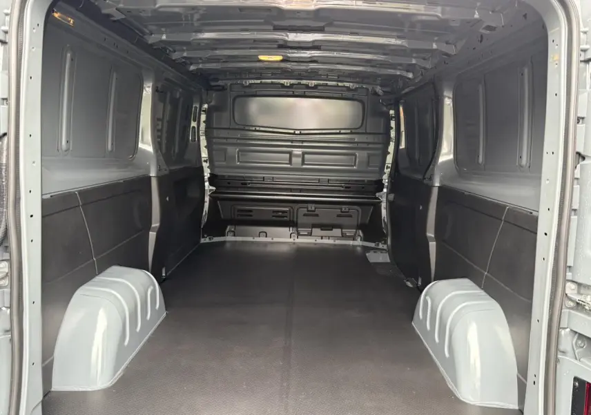 Vue intérieure arrière du Renault Trafic Fourgon gris urbain avec plancher antidérapant et cloison tôlée complète.