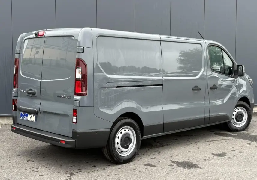 Renault Trafic Fourgon gris urbain vu en 3/4 arrière droit, avec portes latérales et feux arrière visibles.