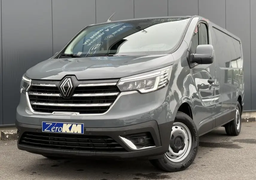 Fourgon Renault Trafic L2H1 gris urbain vu en 3/4 avant droit, avec calandre chromée et jantes acier simples.