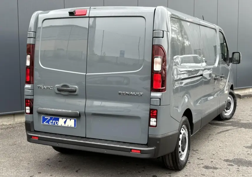 Vue 3/4 arrière droite du fourgon Renault Trafic L2H1 2025 en gris urbain avec porte arrière fermée et jantes acier.