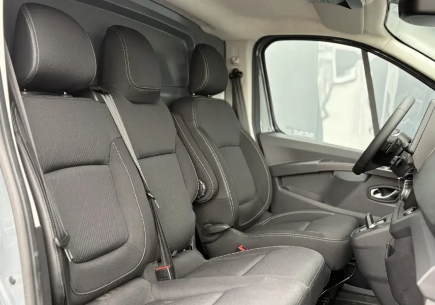 Vue intérieure côté droit du Renault Trafic Fourgon 2025, sièges noirs avec coutures blanches et plancher antidérapant.