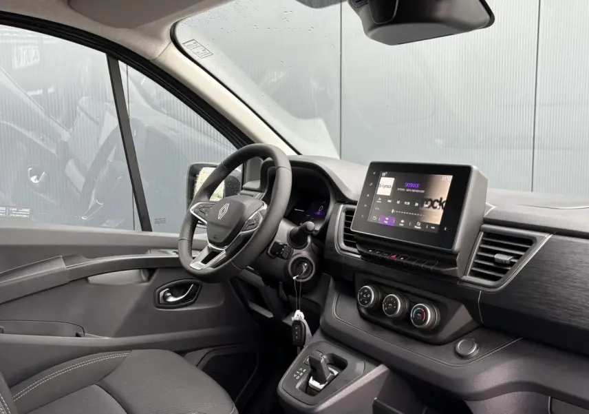 Vue intérieure côté conducteur du Renault Trafic Fourgon 2025, tableau de bord moderne avec écran tactile et volant cuir multifonction.
