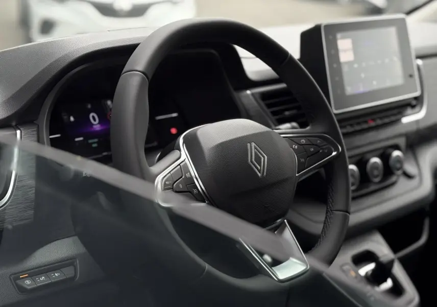 Vue intérieure centrée sur le volant en cuir multifonction du Renault Trafic Fourgon 2025 avec tableau de bord numérique.
